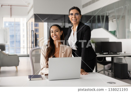 Young apprentice and mature mentor women posing in workspace Young apprentice and mature mentor women posing in workspace 138021193