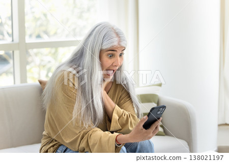 Amazed mature woman gawp at smartphone screen with mouth opened Amazed mature woman gawp at smartphone screen with mouth opened 138021197
