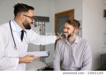 Smiling physician holding hand on patient shoulder greeting with recovery Smiling physician holding hand on patient shoulder greeting with recovery 138021205