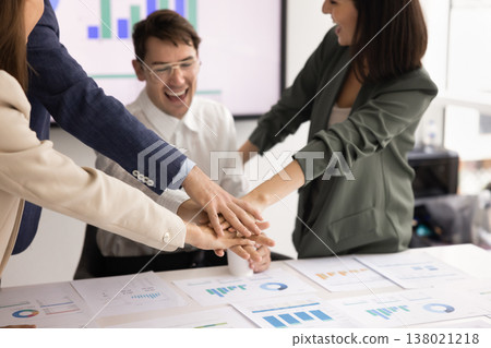 Four colleagues enthusiastically stack their hands together Four colleagues enthusiastically stack their hands together 138021218