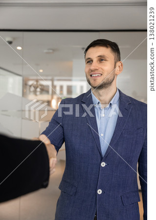 Confident young businessman dressed in suit shaking hands with client Confident young businessman dressed in suit shaking hands with client 138021239