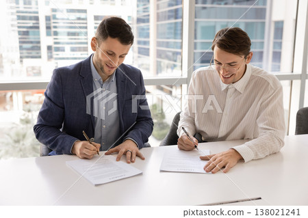 Two businessmen signing contract, feel satisfied with positive negotiation outcome 138021241