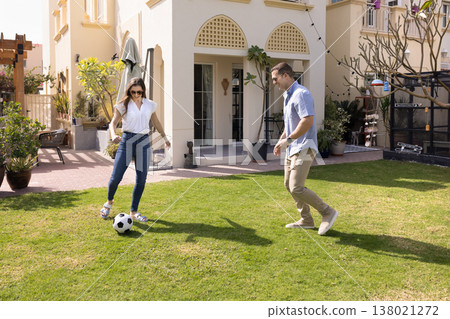 Married couple playing football in backyard of country house 138021272