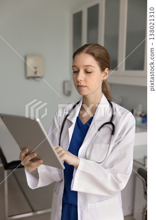 Female nurse or GP in uniform working on tablet device Female nurse or GP in uniform working on tablet device 138021310