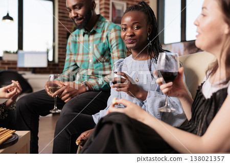 Horizontal shot of smiling, happy, glad young adult african american girl enjoying social life, wine glass at friends, mates, partners apartment, home, house made party, reunion, gathering. Horizontal shot of smiling, happy, glad young adult african american girl enjoying social life, wine glass at friends, mates, partners apartment, home, house made party, reunion, gathering. 138021357