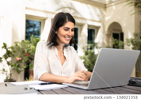 Happy young Latin freelancer woman working on online business project 138021358