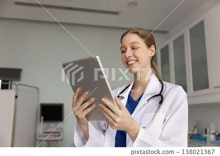 Happy woman doctor videocalling to patient, working online using tablet Happy woman doctor videocalling to patient, working online using tablet 138021367