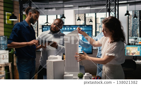 Urban development experts use teamwork to envision a new housing project, studying 3D models for zoning regulations to achieve property. Residential construction master plan. 138021382