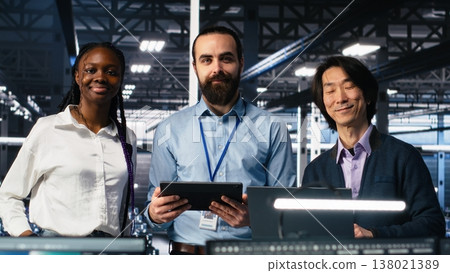 Happy data center coworkers monitoring neural network AI LLM visualization. Jolly workers in high tech facility using devices to oversee servers powering machine learning processes, camera A 138021389