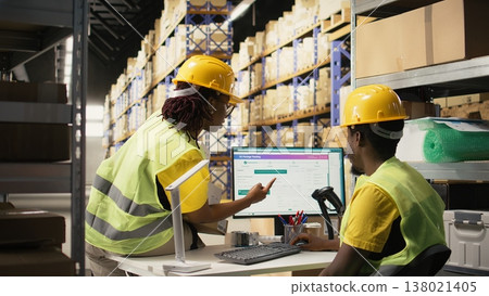 African american workers ensures parcel status on a package tracking software on pc, working in industrial depot for import export operations. Managing inventory and dispatch protocol. Camera A. 138021405