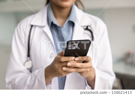 Closeup cropped image of female doctor in coat holding smartphone Closeup cropped image of female doctor in coat holding smartphone 138021413
