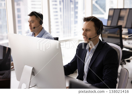 Virtual assistance consultants work using headsets looking at pc displays Virtual assistance consultants work using headsets looking at pc displays 138021416