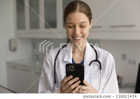 Smiling female doctor using smartphone at workplace Smiling female doctor using smartphone at workplace 138021434