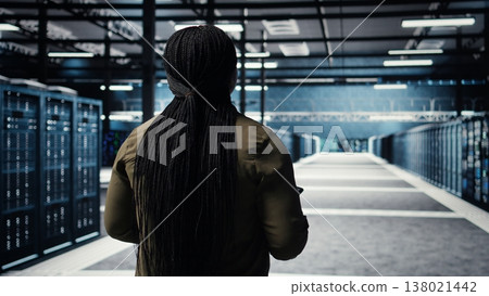 Data center system administrator monitors data center metrics on tablet to enhance operational effectiveness. IT expert in server room using analytics program to predict performance, camera A 138021442