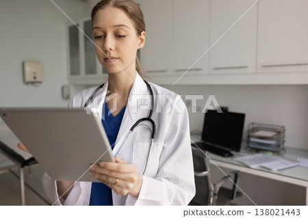 Serious Argentinian nurse working on tablet device in clinic office 138021443
