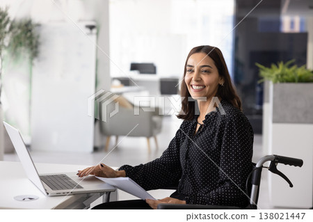 Positive Middle Eastern female worker in wheelchair using laptop computer 138021447