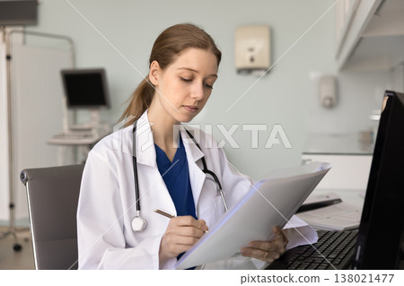 Doctor making notes while holds patient anamnesis or files 138021477