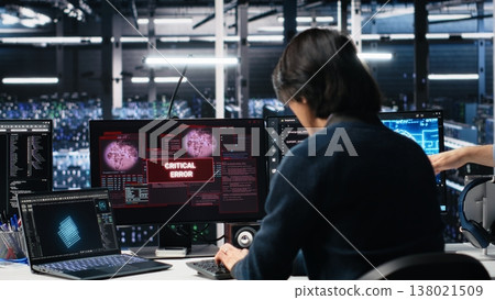 Data center team of engineers trying to fix critical error warning while using AI. Server farm teamworking colleagues repairing glitch popup while using artificial intelligence tech, camera A 138021509