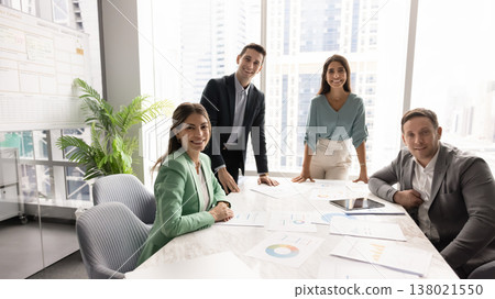 Motivated multiethnic professionals team posing around table in glass office Motivated multiethnic professionals team posing around table in glass office 138021550