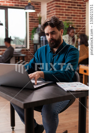 Busy businessman analyzing company statistics typing marketing strategy planning business collaboration. Entrepreneur man brainstorming ideas while working at brick wall startup office Busy businessman analyzing company statistics typing marketing strategy planning business collaboration. Entrepreneur man brainstorming ideas while working at brick wall startup office 138021551