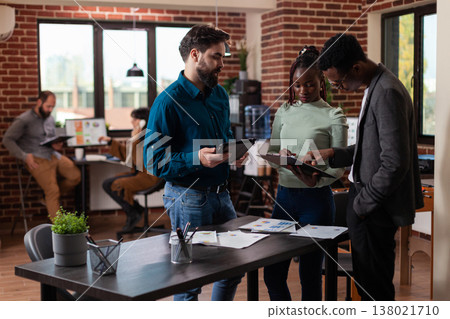 Diverse businesspeople analyzing marketing statistics on tablet computer working at company project in startup office. Multiethnic team brainstorming ideas planning business collaboration. Diverse businesspeople analyzing marketing statistics on tablet computer working at company project in startup office. Multiethnic team brainstorming ideas planning business collaboration. 138021710