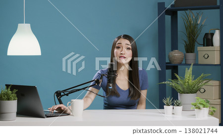 POV of influencer filming online podcast on camera in studio, using recording equipment. Female vlogger broadcasting live discussion on social media, using laptop at desk. Tripod shot. POV of influencer filming online podcast on camera in studio, using recording equipment. Female vlogger broadcasting live discussion on social media, using laptop at desk. Tripod shot. 138021744