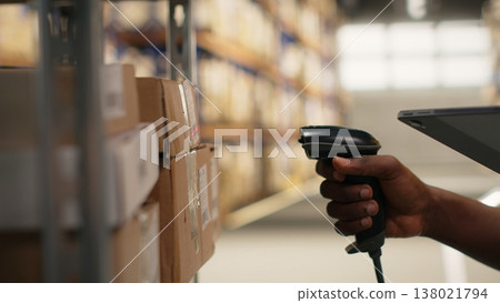 Close up of logistics staff scanning airway bill tags for inventory registration, updating records in import export system on tablet. Retail e-commerce operations in industrial depot. Camera B. Close up of logistics staff scanning airway bill tags for inventory registration, updating records in import export system on tablet. Retail e-commerce operations in industrial depot. Camera B. 138021794