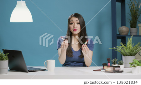POV of content creator doing lipstick review on vlogging camera, recording online videoblog in studio. Female influencer recommending makeup product cosmetics on social media. Tripod shot. 138021834