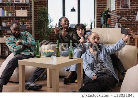 Young people having fun with photos taken on smartphone camera, creating memories together at social gathering with beer and snacks. Friends taking pictures drinking and relaxing. Young people having fun with photos taken on smartphone camera, creating memories together at social gathering with beer and snacks. Friends taking pictures drinking and relaxing. 138021845