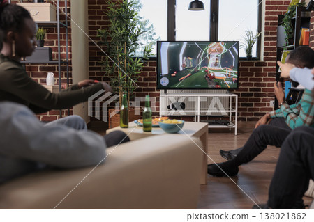 Diverse people playing video games competition on tv, enjoying shooting game play on console at hangout with friends. Having fun with shooter strategy, leisure activity with alcohol. Diverse people playing video games competition on tv, enjoying shooting game play on console at hangout with friends. Having fun with shooter strategy, leisure activity with alcohol. 138021862