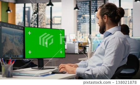Worker uses green screen mockup PC to optimize advanced VAWT wind farm layout, enhancing clean energy production. Technician uses chroma key computer to do futuristic wind turbine simulation, camera B 138021878