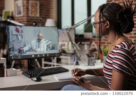 Patient talking with doctor on video call, woman chatting with therapist online, taking notes in notebook. Telemedicine, remote general practitioner appointment, medical consultation on internet Patient talking with doctor on video call, woman chatting with therapist online, taking notes in notebook. Telemedicine, remote general practitioner appointment, medical consultation on internet 138022070