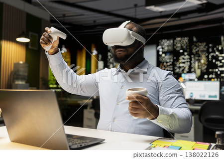 Black male employee using virtual reality glasses to draft a plan for goals, forecasting projections and documenting risk assessment. Organizing agenda to align with business objectives. 138022126