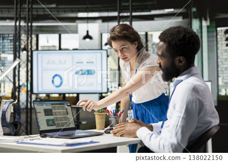 Male and female colleagues working together on business reports, sharing insights and reviewing data on laptop. White businesswoman and black man planning financial strategies for corporate success. Male and female colleagues working together on business reports, sharing insights and reviewing data on laptop. White businesswoman and black man planning financial strategies for corporate success. 138022150