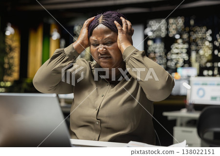 Angry tensed businesswoman rubbing her head and feeling overwhelmed, expressing weariness and agitation due to intense workload and overtime late at night. Anxious person in office. Angry tensed businesswoman rubbing her head and feeling overwhelmed, expressing weariness and agitation due to intense workload and overtime late at night. Anxious person in office. 138022151
