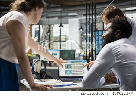 Black man and two caucasian colleagues analyzing charts, graphs and financial data on laptop. Business analysts collaborating on investment strategies and company reports in office. 138022177