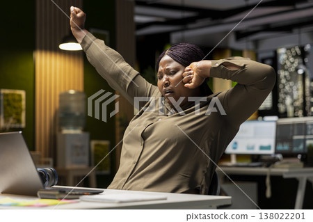 Drained restless woman yawning and stretching her back muscles, going into mental haze and weariness with late night work. Employee in discomfort feeling anxious and overwhelmed. Drained restless woman yawning and stretching her back muscles, going into mental haze and weariness with late night work. Employee in discomfort feeling anxious and overwhelmed. 138022201