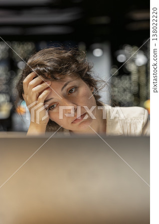 Discouraged woman creating plans and documenting objectives to share with executives during the next morning meeting. Employee drained in a mental haze doing overtime, pushing limits. 138022220