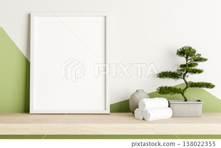 Empty white frame with towels and bonsai pot on wooden hanging shelf in a white and green wall room. Empty white frame with towels and bonsai pot on wooden hanging shelf in a white and green wall room. 138022355