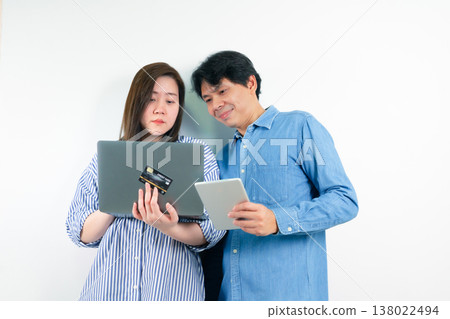 asian business couple 30s to 40s with blue shirt use credit card for paid and laptop for check profit of startup business with good feeling and white isolated background asian business couple 30s to 40s with blue shirt use credit card for paid and laptop for check profit of startup business with good feeling and white isolated background 138022494