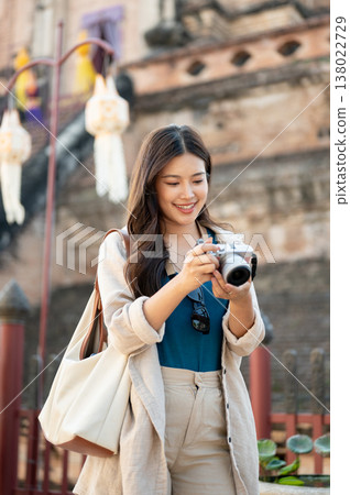 Pretty asian woman checking camera looking at photo standing under ancient pagoda in buddhist temple 138022729