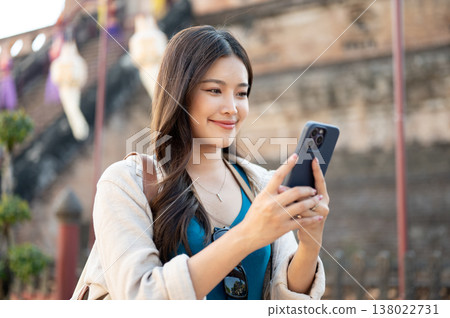 Pretty asian woman looking at phone while standing walking around ancient pagoda in buddhist temple. 138022731