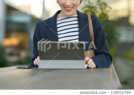 A Japanese businesswoman in her 30s working outdoors using a tablet. A Japanese businesswoman in her 30s working outdoors using a tablet. 138022794