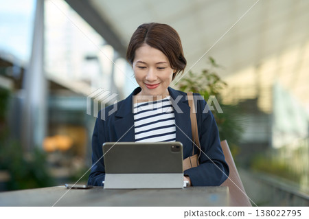 一位30多歲的日本女商人正在戶外使用平板電腦工作。 138022795