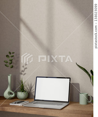 White screen laptop with book and coffee mug aside green plant on wooden table and sunlight on wall. 138023099