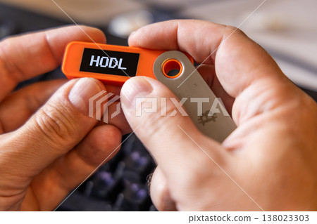 hardware Bitcoin wallet in a hands with message Hodl on screen hardware Bitcoin wallet in a hands with message Hodl on screen 138023303