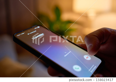 Hand holding smartphone with unknown incoming call at home Hand holding smartphone with unknown incoming call at home 138023417