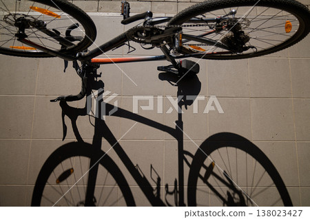 Top view of bicycle with shadow on sunlit pavement Top view of bicycle with shadow on sunlit pavement 138023427