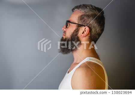 Man with beard and glasses poses against a simple gray background Man with beard and glasses poses against a simple gray background 138023694