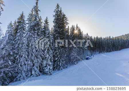Snow-covered trees and a blue tent in a forest at winter sunrise Snow-covered trees and a blue tent in a forest at winter sunrise 138023695